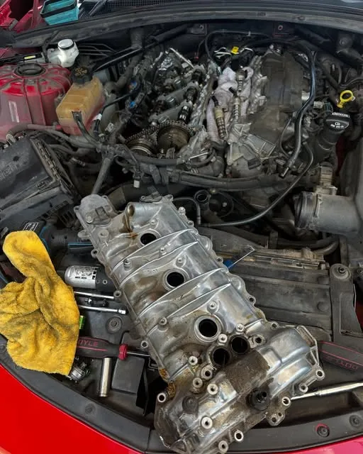 Engine bay of a red car with the top of the engine removed for repair