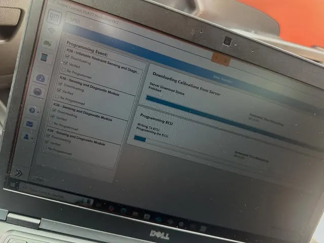 Laptop screen showing a vehicle control module being programmed