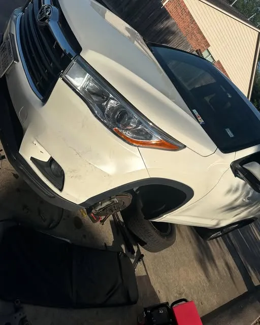 White SUV raised on a jack with the front wheel removed